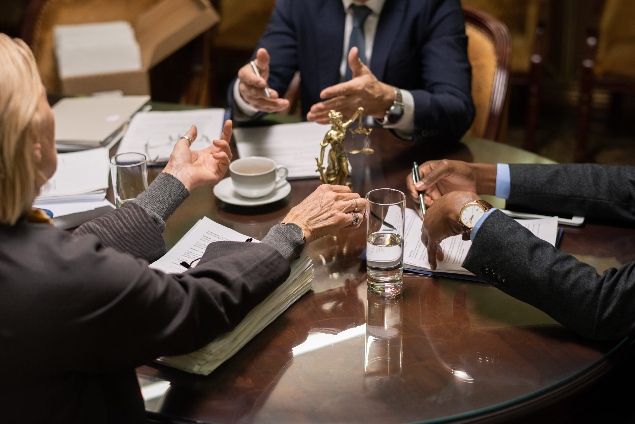 Hands of three contemporary lawyers during discussion Hands of three contemporary intercultural lawyers during discussion of working points by table with juridical documents